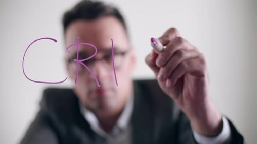 Man Writes the Word Crisis on Glass