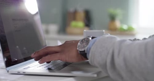 Männliche Freiberufler tippen auf einem Laptop, arbeiten an einer Theke in der heimischen Küche