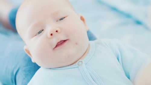 Mutter spielt mit ihrem neugeborenen Sohn mit tiefblauen Augen in einem hellen Raum