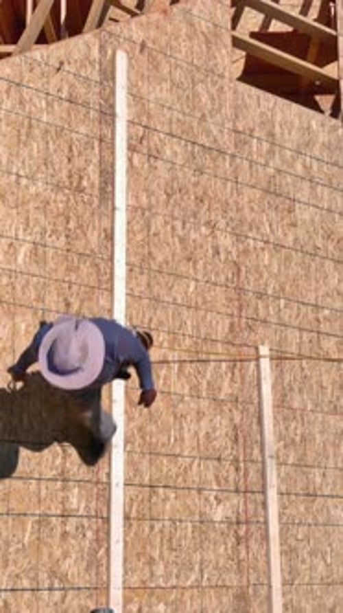 Construction Worker Installs Roof on Building at a Sunny Site in the Afternoon
