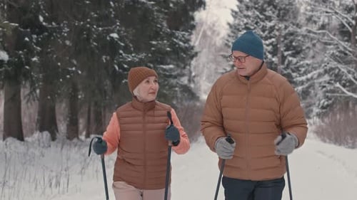 Active Elderly Couple Nordic Walking in Winter Forest