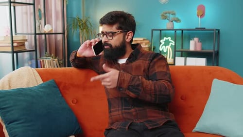 Man Talking Angrily on Phone Sitting on Couch