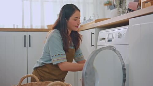 Woman Loading Clothes Into Washing Machine at Home