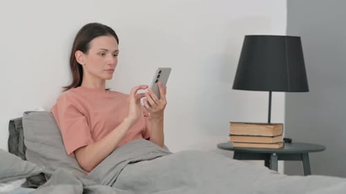 Woman Using Smartphone While Lying in Bed