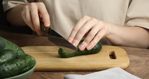 Woman slicing cucumber on a cutting board