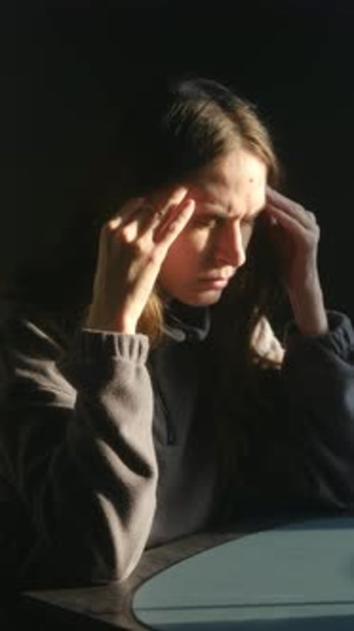 Frustrated woman massages temples indoor with golden light