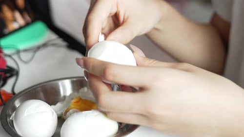 Close up shot of hands peeling boiled eggs. Peel chicken eggs to prepare food.