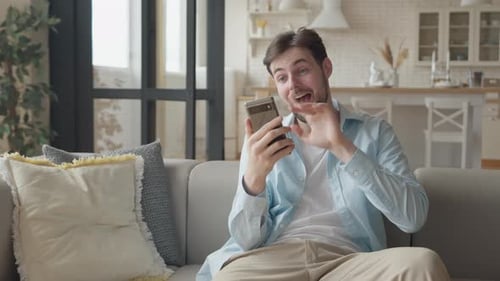 Man Video Calling on Phone While Sitting on Couch