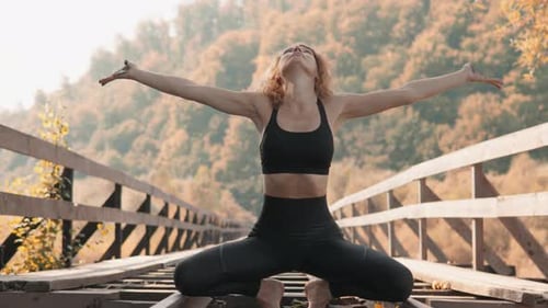 A Serene Woman Practices Yoga on an Old Bridge Surrounded By Vibrant Autumn Leaves Creating a