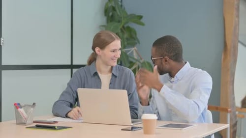 Coworkers Collaborate on Laptop in Modern Office