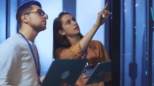 Technicians Inspecting Data Servers with Tablet and Laptop