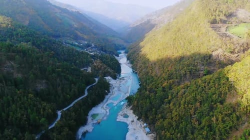 Drone filmé en vol entre une vallée verdoyante et étroite, la rivière Tama Koshi coulant entre eux pendant l'or