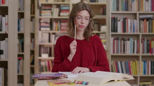 College student in library studying gets brainwave, jot down idea in book