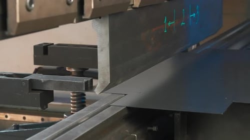 Ein Metallblech, das auf eine Maschine gelegt wird, die es langsam faltet