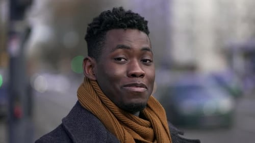Happy black man smiling at camera standing outside in street looking at camera