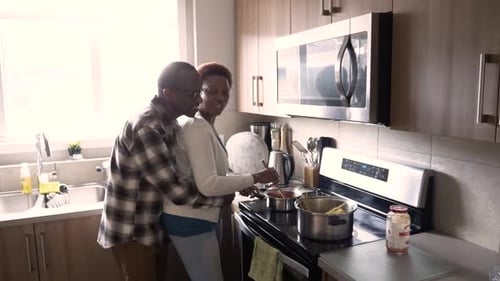 Affectionate couple cooking spaghetti together in a kitchen