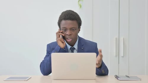 Young Adult Man Arguing on the Phone at Work