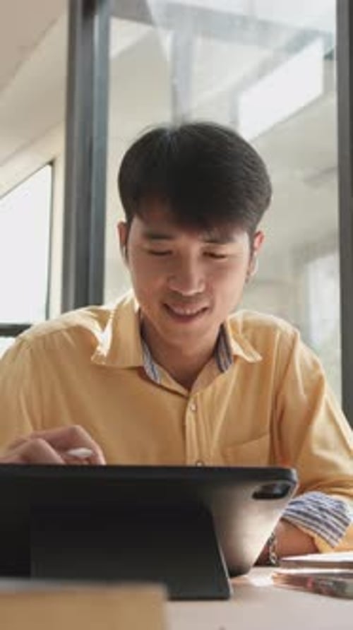 Young Man Uses Tablet with Stylus Indoors