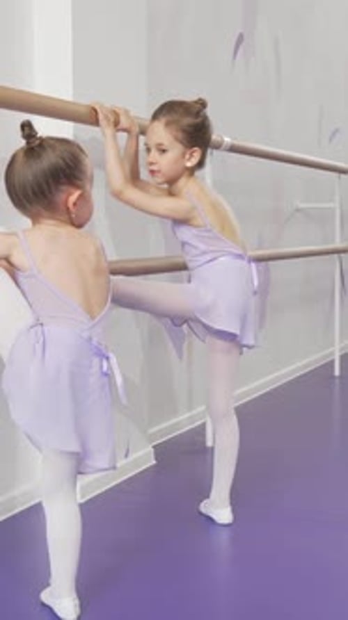 Two Adorable Little Ballerinas Stretching Gracefully at Ballet School