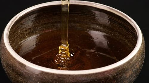 Fresh Honey Flowing Into A Bowl On The Black Background, Sweet Dessert