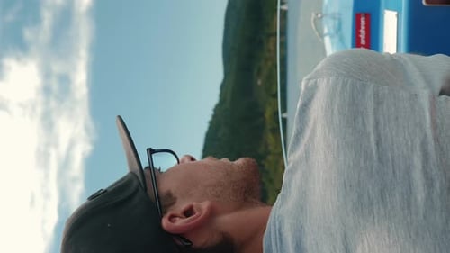 Man driving electric boat ship on mountain lake. Vertical video