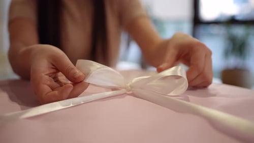 Woman Tying Bow on Pink Birthday Gift