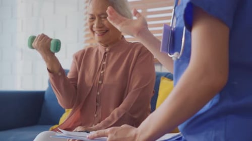 Senior Woman Lifts Dumbbell With Health Professional