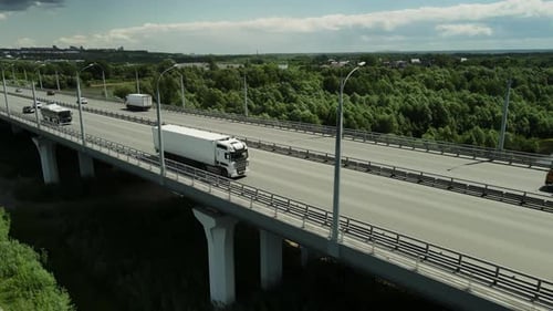 Trucks and Cars Crossing Bridge Over Green Nature