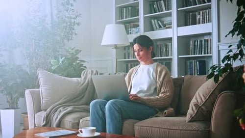 Woman Uses Laptop on Couch in Sunlit Home