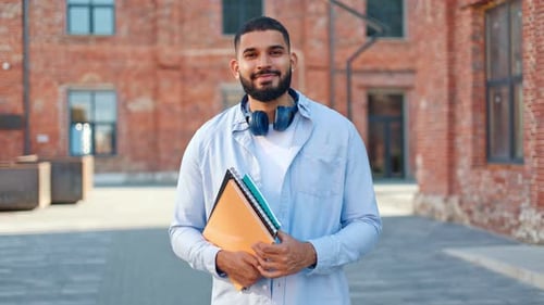 Smiling Young Adult Student Holding Books in Urban Setting