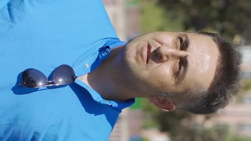 Vidéo verticale de L'homme suffoque à cause du temps chaud et ensoleillé à l'extérieur.
