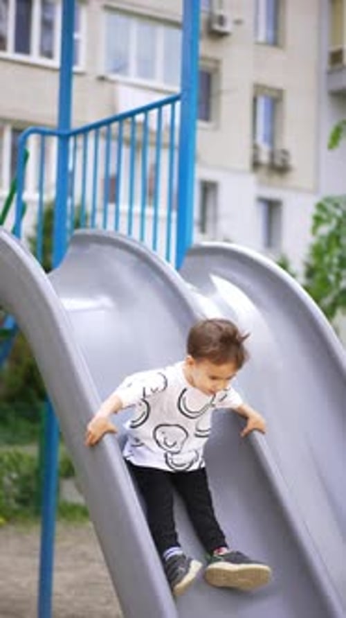 Young Boy Slides Down a Playground Slide