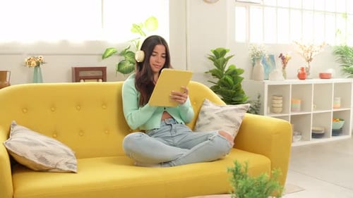 Young Woman Using Tablet on Yellow Sofa
