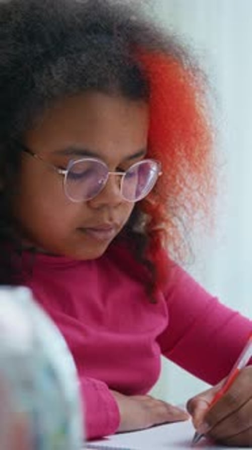 Une jeune fille aux cheveux colorés se concentre sur le dessin dans un environnement d'apprentissage lumineux