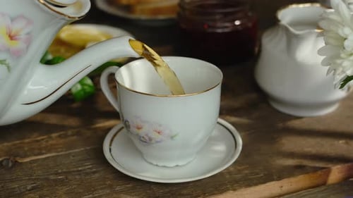 Pouring Black Tea From Teapot Into Porcelain Cup