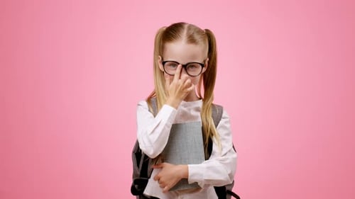 Junges Mädchen mit Brille, das ein Buch hält und vor rosafarbenem Hintergrund lächelt
