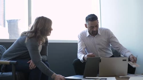 Business colleagues collaborate with laptops during an office meeting