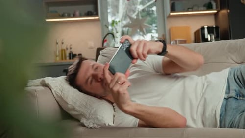 Young Adult Lying on Couch Using Mobile Phone