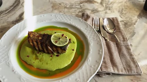 Serving of Tasteful Dish with Smoked Sea Bass Laying on Mashed Beans Puree on White Round Plate