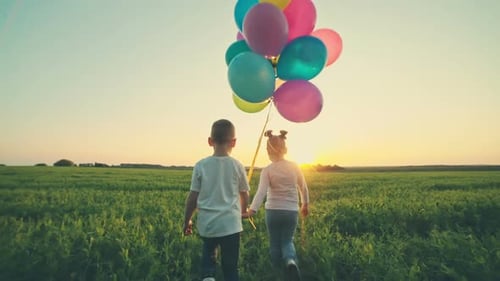 Happy Sister and Brother with Balloons Walking on the Spring Field