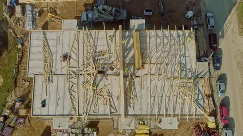 Luftaufnahme von Arbeitern, die auf der Baustelle arbeiten, Holzbinder des Gebäudes. - Nach oben kippen