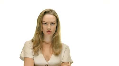 A close-up of a woman with an annoyed facial expression, raising her finger to her mouth and making