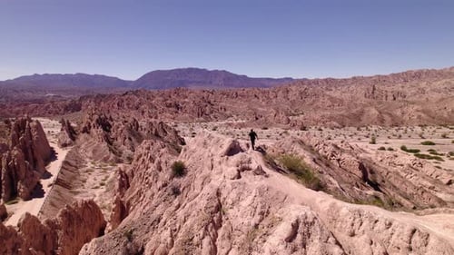 A man Exploring Stunning Rock Formations and Vast Landscapes in a Remote Desert Region During Bright