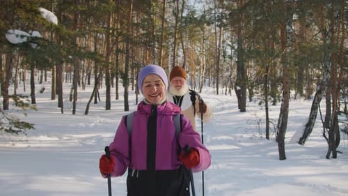 Cheerful Senior Couple Enjoying Nordic Walking in Snow in Park