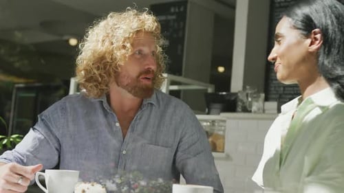Happy diverse couple drinking coffee and talking in cafe