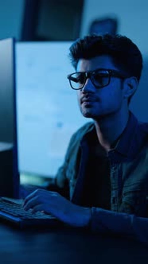 Junger Programmierer, der spät in der Nacht an einem Computer arbeitet. Hacker, der Code in einem dunklen Raum
eingibt