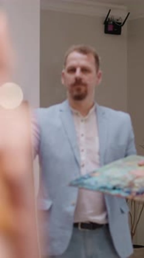 Man Paints on Canvas with Palette Indoors