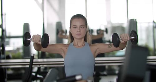Fitness Girl Lifts Weights in a Sports Club A Woman Performs Strength Exercises with Dumbbells in