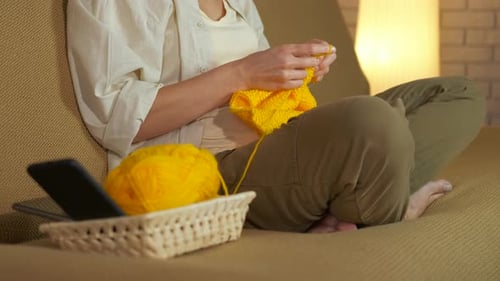 Woman Knitting on Couch with Yellow Yarn