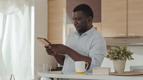 Man Uses Tablet and Drinks Coffee at Home